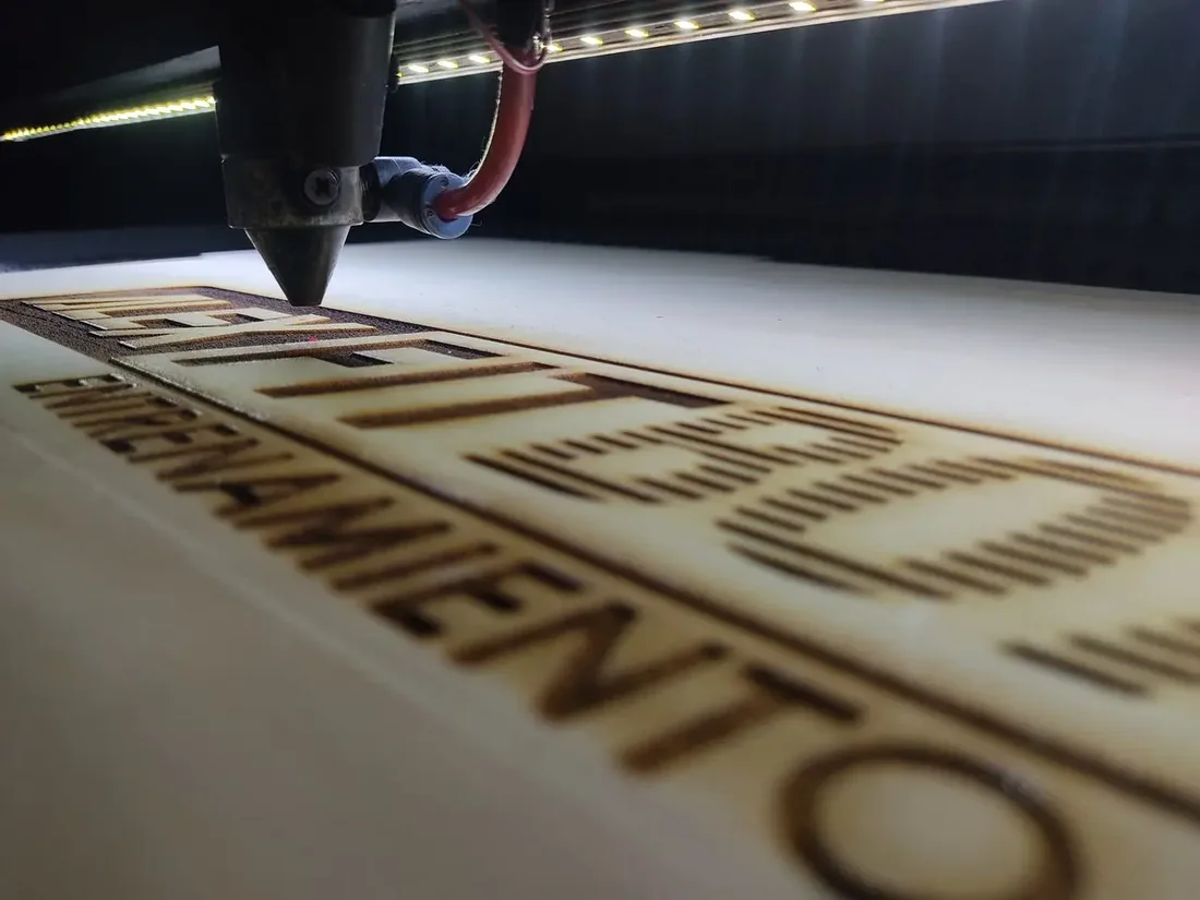 Cabezal de la máquina láser grabando una placa de madera